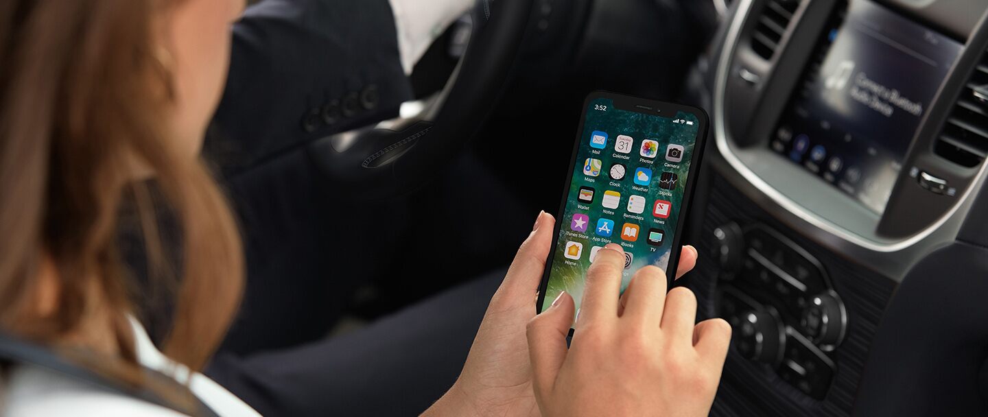 Manos conectando un teléfono a un carro