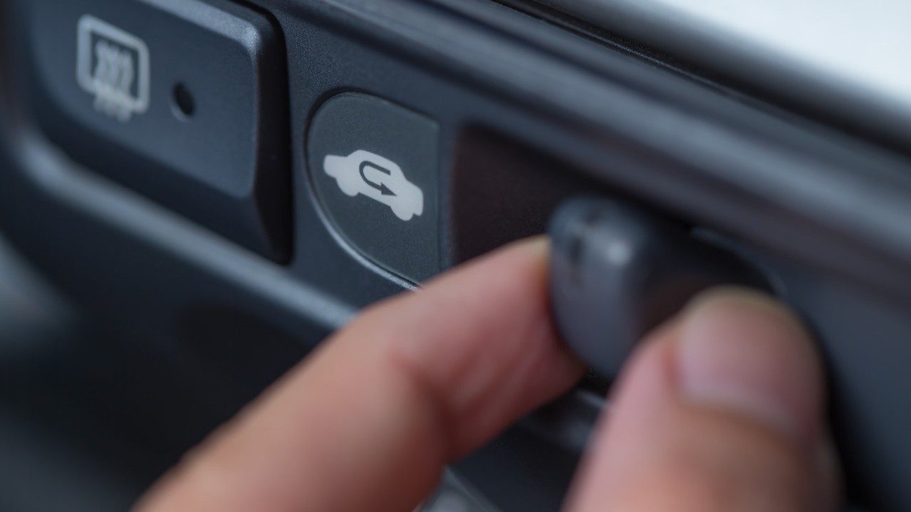 Mano presionando botón de recirculación del auto