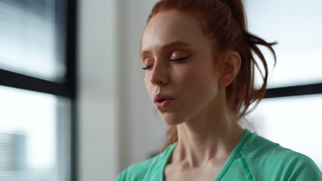 cara de cerca de la mujer joven tranquila meditando con los ojos cerrados y haciendo