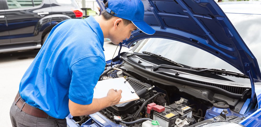 Persona revisando motor de un coche