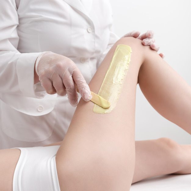 Mujer aplicando cera en pierna correctamente
