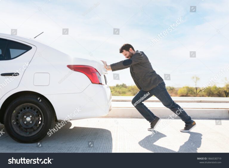 stock photo tired man in his s trying hard to push his dead car to move it to the side of the road 1866530719
